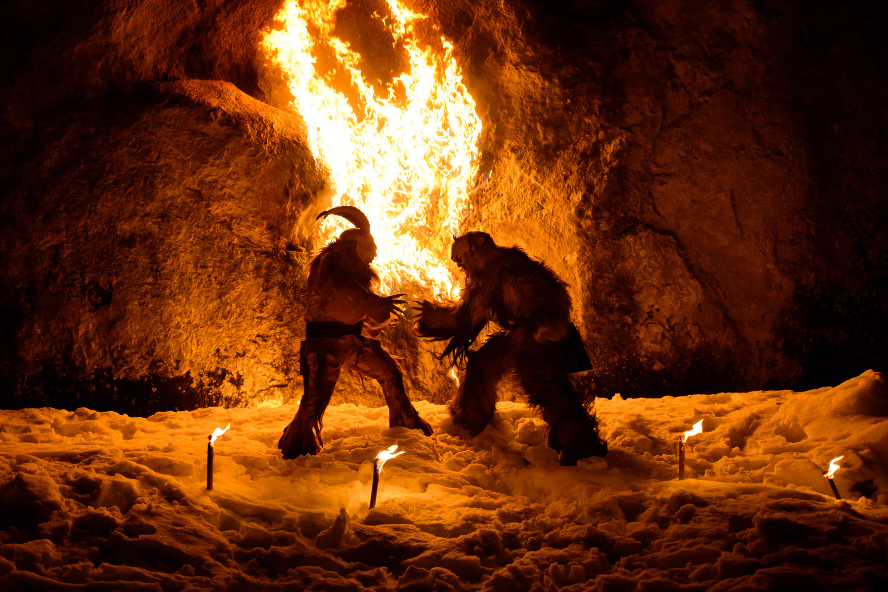 due krampus lottano davanti al fuoco