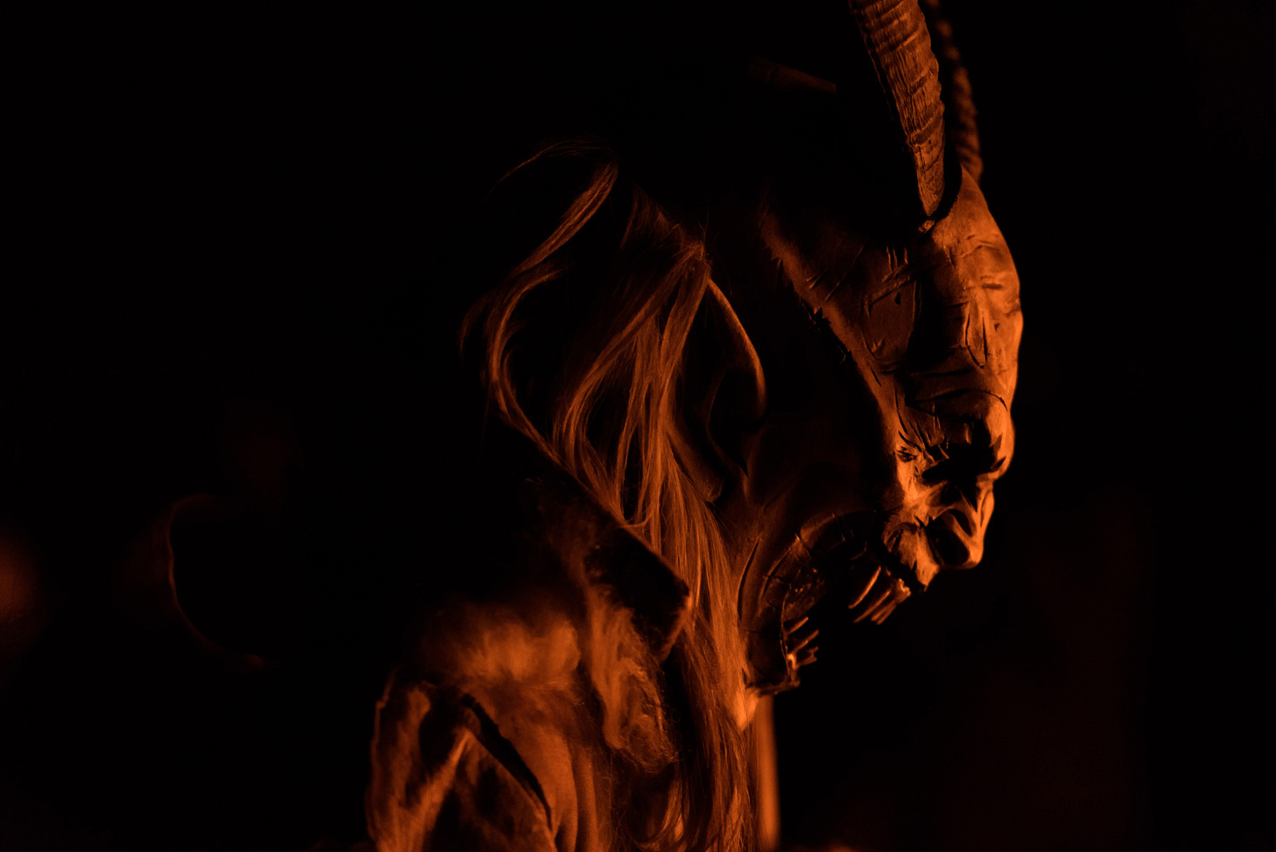 maschera di krampus di profilo davanti al fuoco